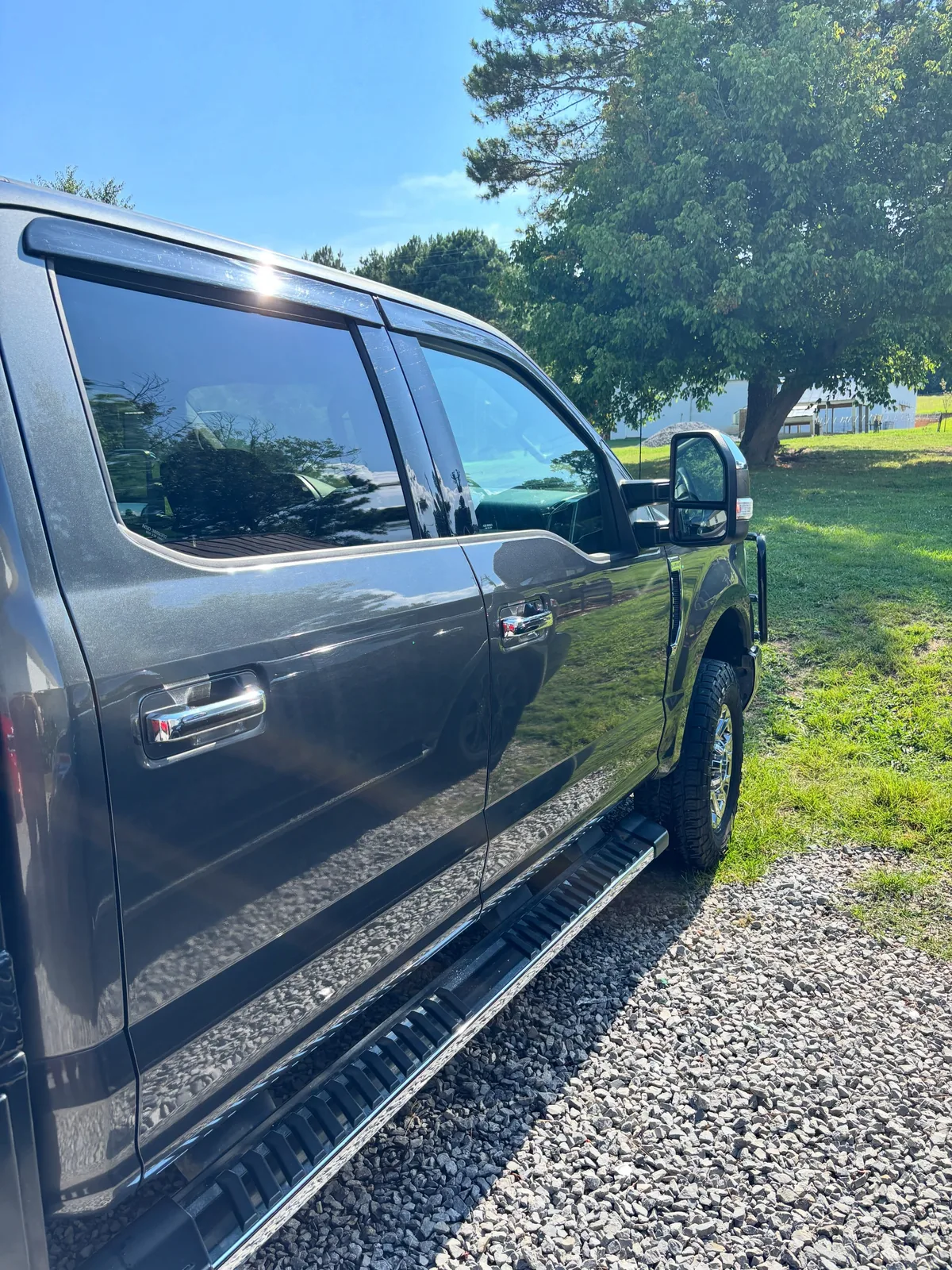 Grey Ford Super Duty crew cab with polished doors and chrome running boards